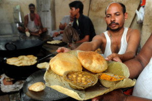 Indian food vendor Naradh Muni (R) holds a plate made of leaves with pooris (fried puffed wholewheat flat bread) and channa or chole masala (chickpeas) at The 'No Profit and No Loss' sweets shop in  the ground of The Durgiana Temple in Amritsar on September 30, 2009. One plate of channa with two pooris and accompanying pickles sells for Indian Rupees fourteen (USD 0.29).   AFP PHOTO/NARINDER NANU (Photo credit should read NARINDER NANU/AFP/Getty Images)